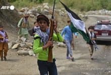 Afghan children carry rifles and a Panjshir National Resistance Front flag along a road in the Dara district of Panjshir province