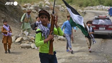Afghan children carry rifles and a Panjshir National Resistance Front flag along a road in the Dara district of Panjshir province